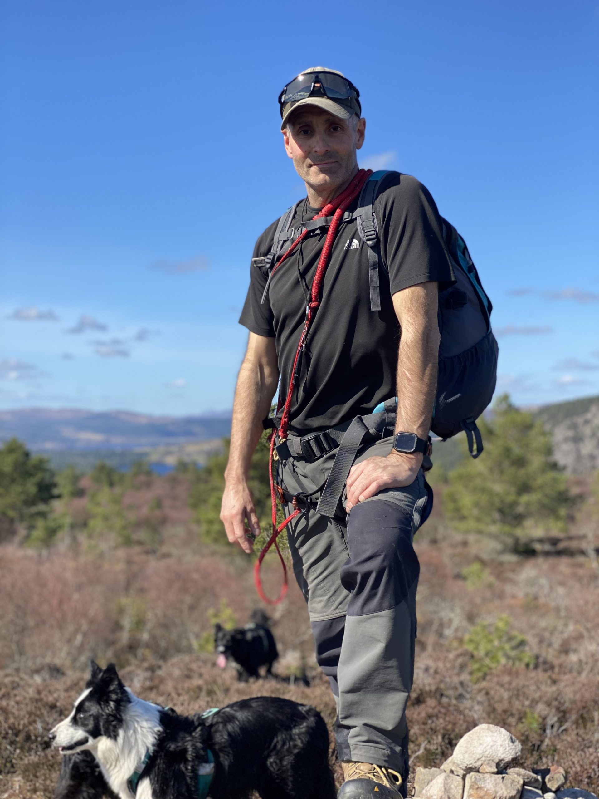 Rob from RoMack Garden Services outdoors in hiking gear with his dogs